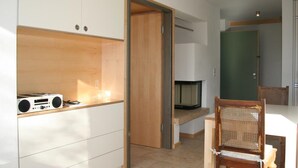 A room with a wooden shelf, a chair, and a door leading to another room. - Apartment 1 with mountain view (Söllhuben)