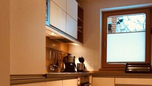 A kitchen with white cabinets, a built-in oven, and a window with a view of the outside. - Apartment 1 with mountain view (Söllhuben)