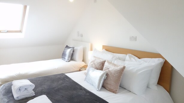 Ein Schlafzimmer mit zwei Betten, einem Fenster und einem Holzkopfende.