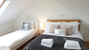 Ein Hotelzimmer mit zwei Einzelbetten, einem Nachttisch mit Lampe und Blick zum Himmel durch ein Fenster.