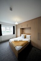Una habitación de hotel moderna con una cama grande, un armario de madera y una ventana con cortinas.