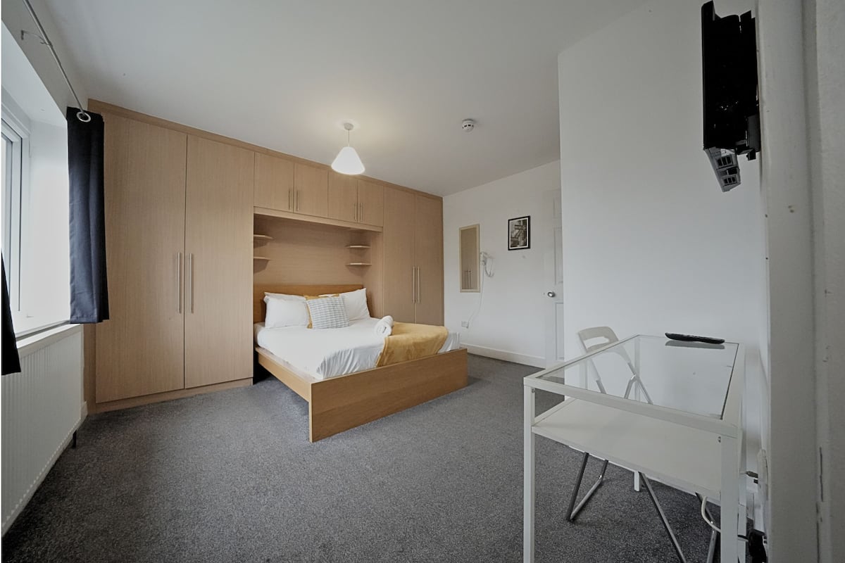 Ein Schlafzimmer mit Bett, Schreibtisch und Kleiderschrank.