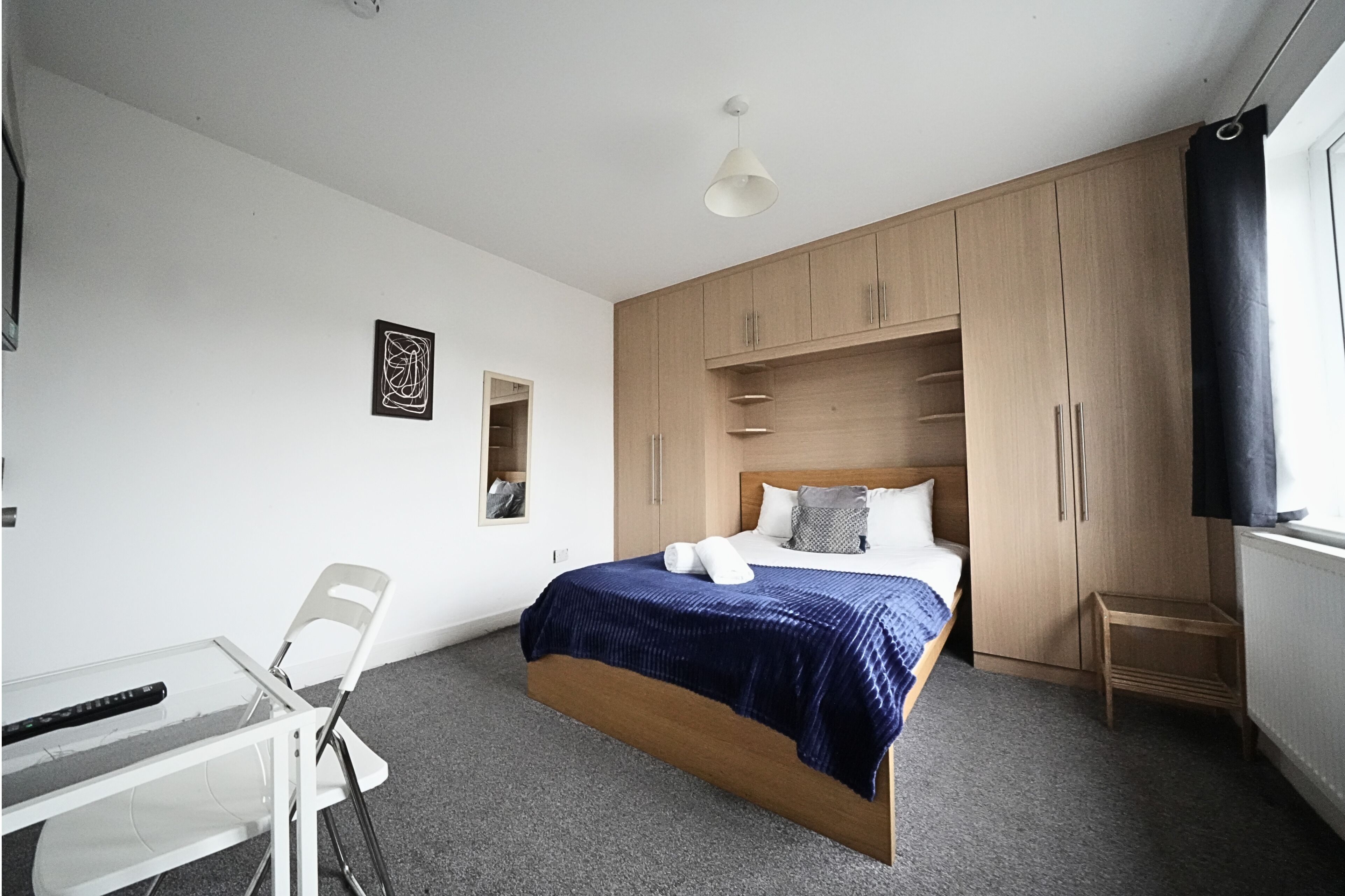 A bedroom with a bed, a desk, a chair, and a wardrobe.