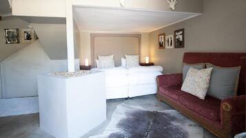 A bedroom with a large bed, a red sofa, and a cowhide rug.