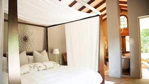 Une chambre à coucher avec un lit à baldaquin, un élément décoratif mural et une vue sur la salle de bain.