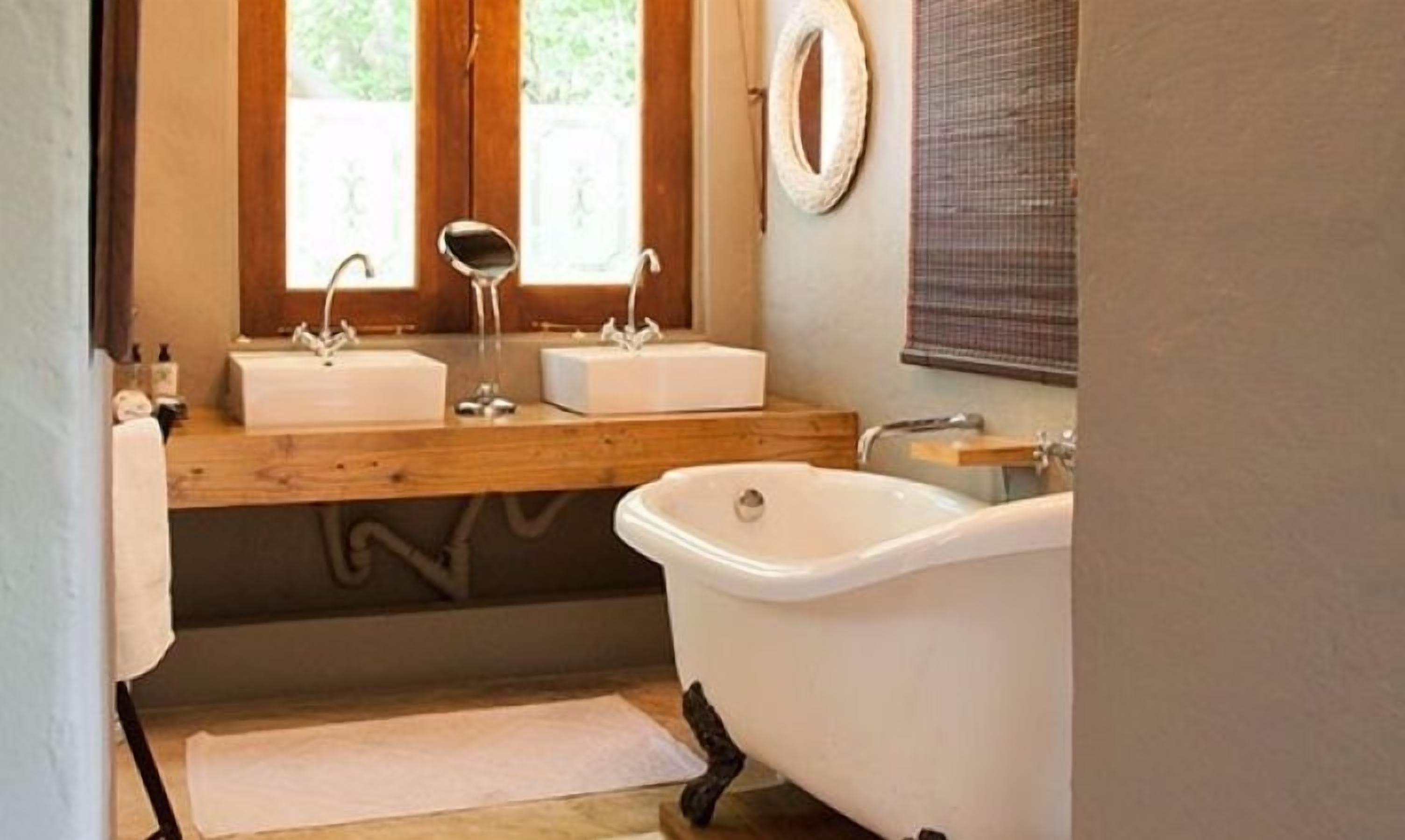 A bathroom with two sinks, a bathtub, and a mirror.