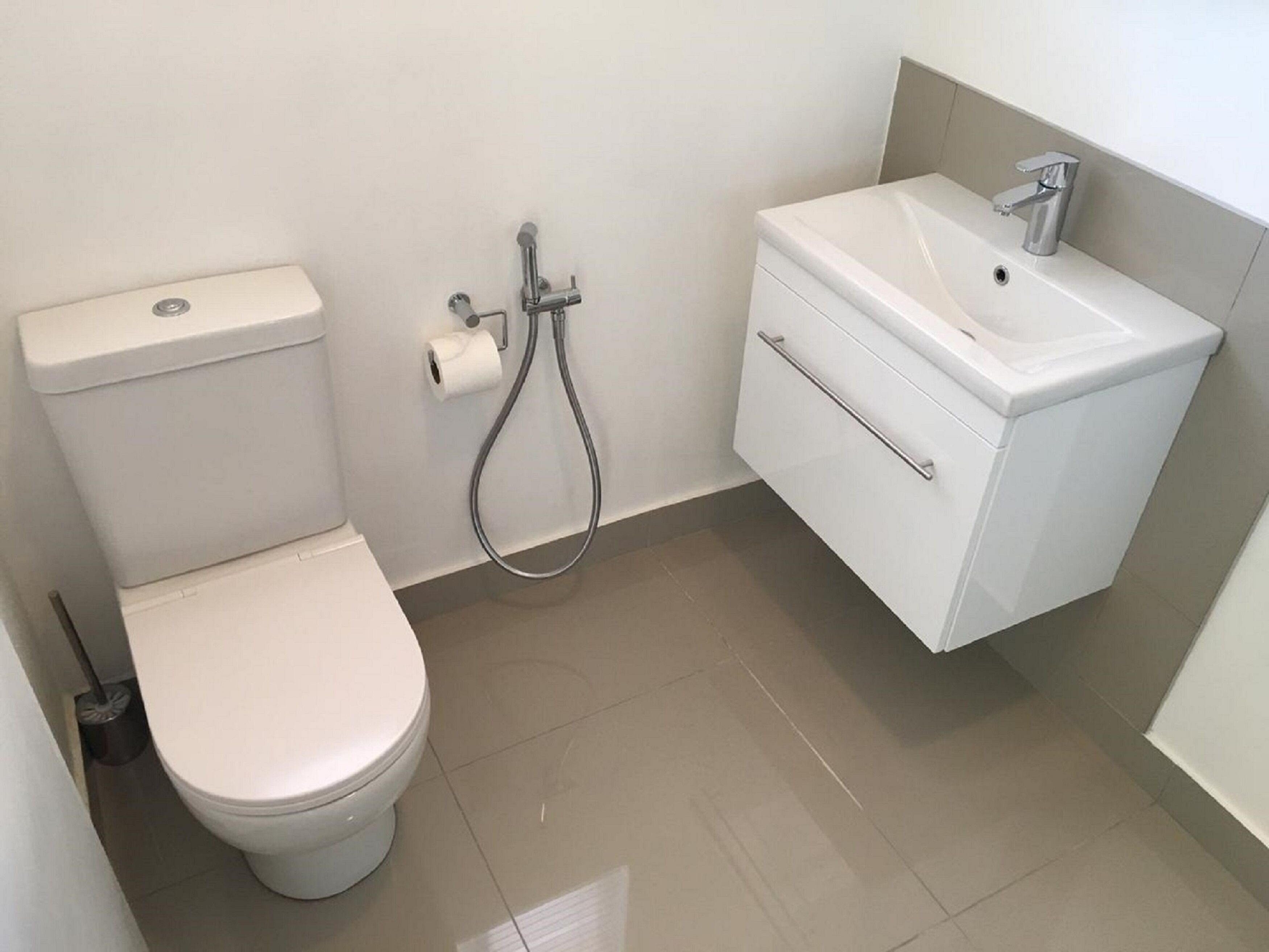 A small bathroom with a toilet, a shower, and a sink.
