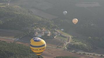 Un globo aerostático con el texto "CIRAROLLES PETROM" sobrevolando un paisaje con edificios y carreteras.