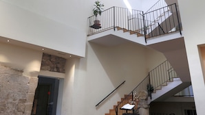 Un intérieur à plusieurs niveaux, avec un escalier, un tonneau en bois et une plante en pot.