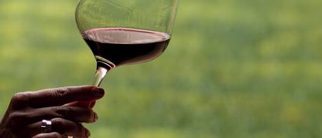 A hand holding a wine glass with a blurred green background.