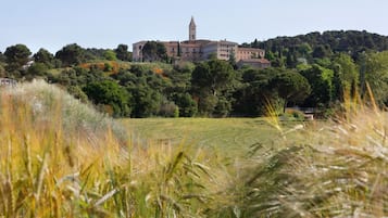 A large building with a tower, surrounded by lush greenery and fields.