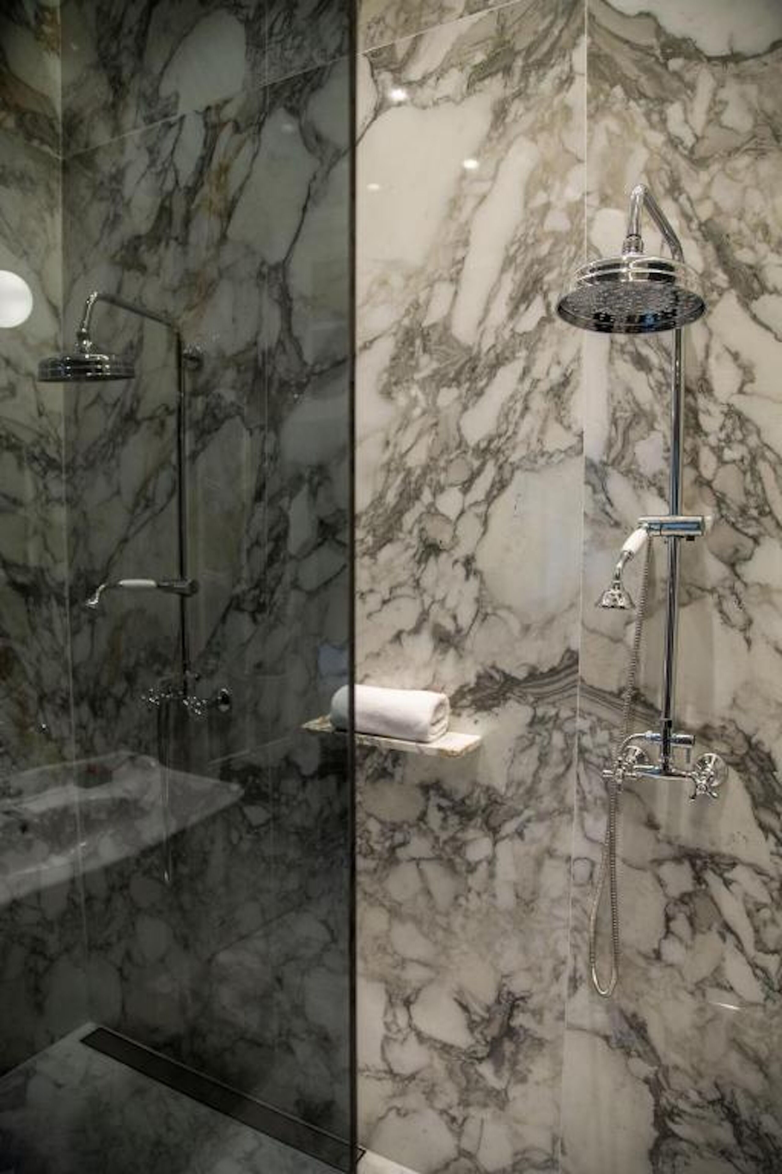 Ein modernes Badezimmer mit Marmorwänden und zwei Duschkabinen.