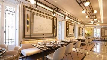 Un comedor amplio con varias mesas y sillas, arte de pared elegante y un diseño moderno de techo.