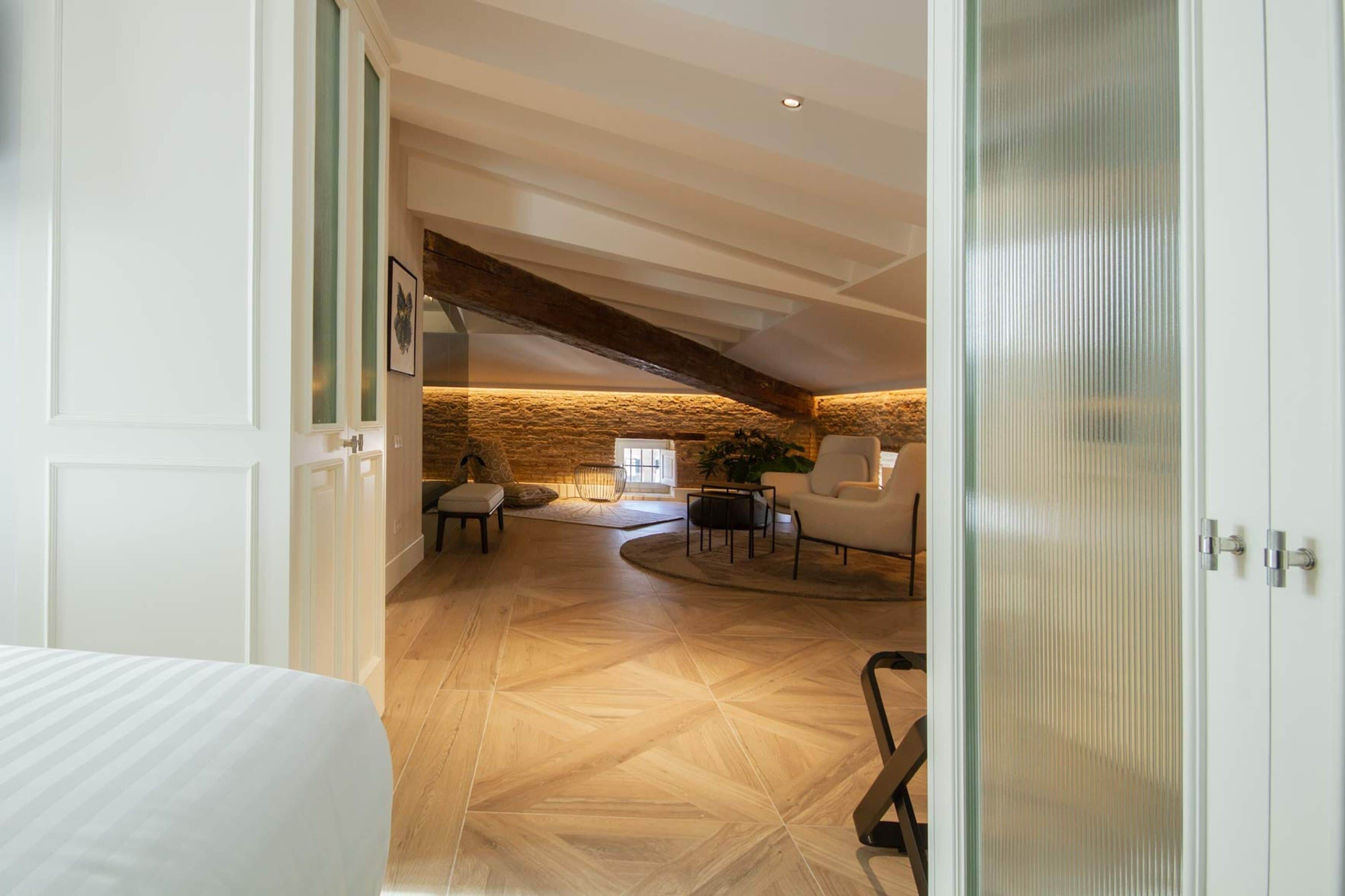 Una habitación amplia con techo alto, pared de piedra y ventana grande.