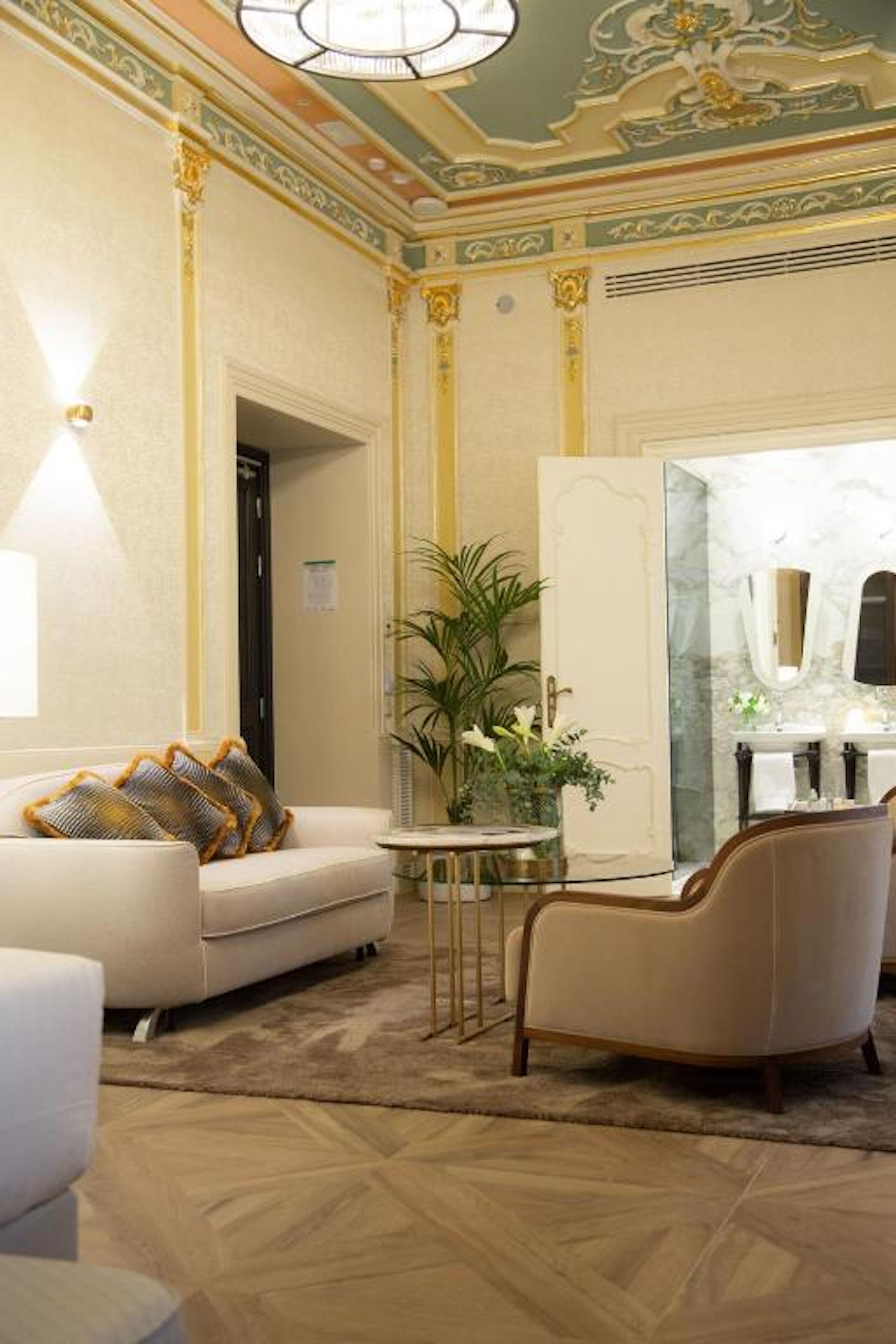 Una habitación lujosa con sofá, sillón y espejo.