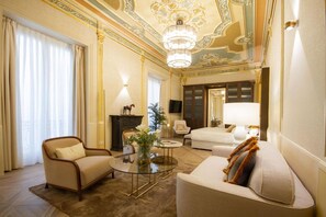 A luxurious living room with a chandelier, a sofa, a chair, and a coffee table. - MYR Palacio Vallier (Valencia)