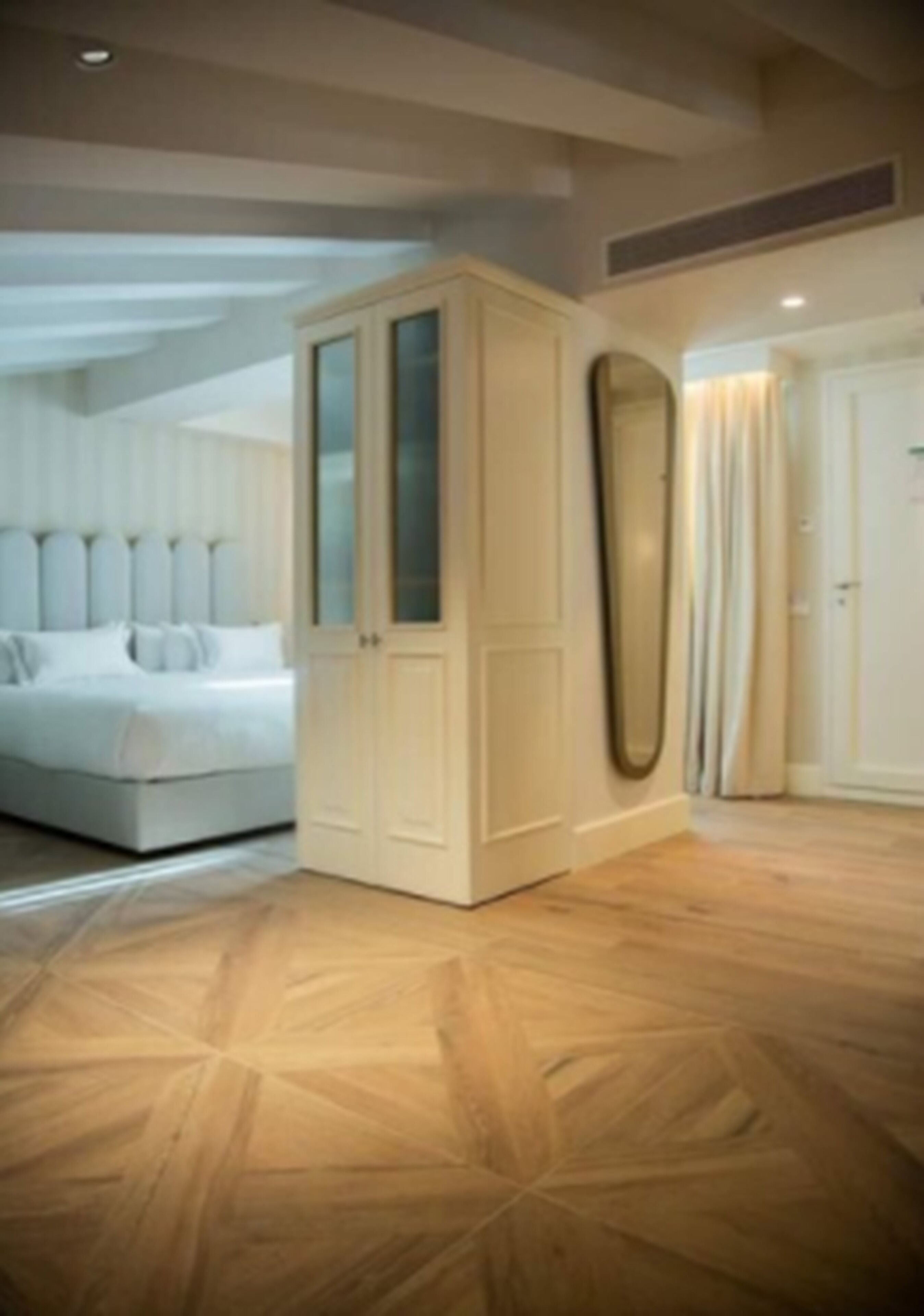 A bedroom with a bed, a wardrobe, and a mirror on the wall.