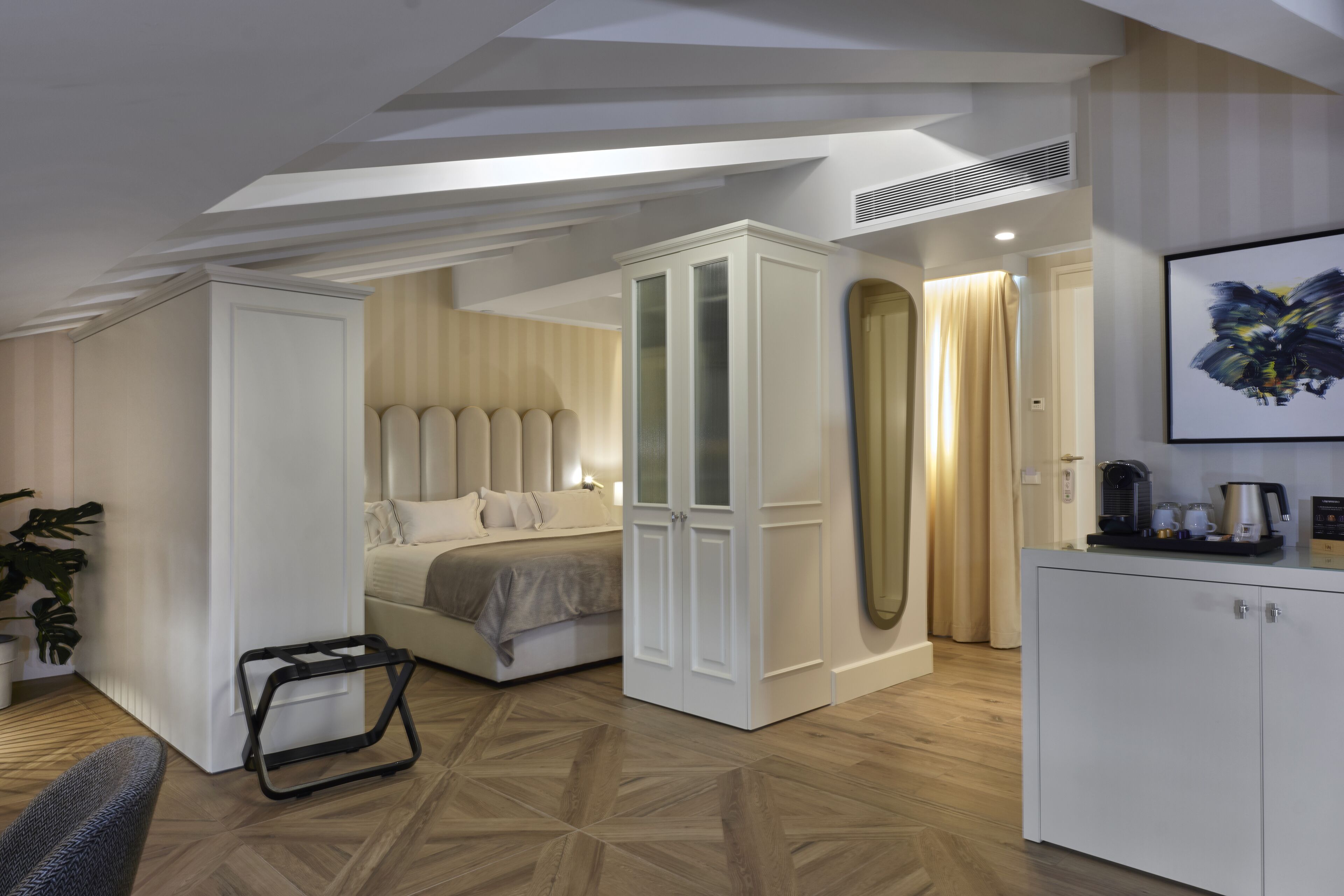 Quarto moderno com cama, guarda-roupa e escrivaninha com máquina de café.