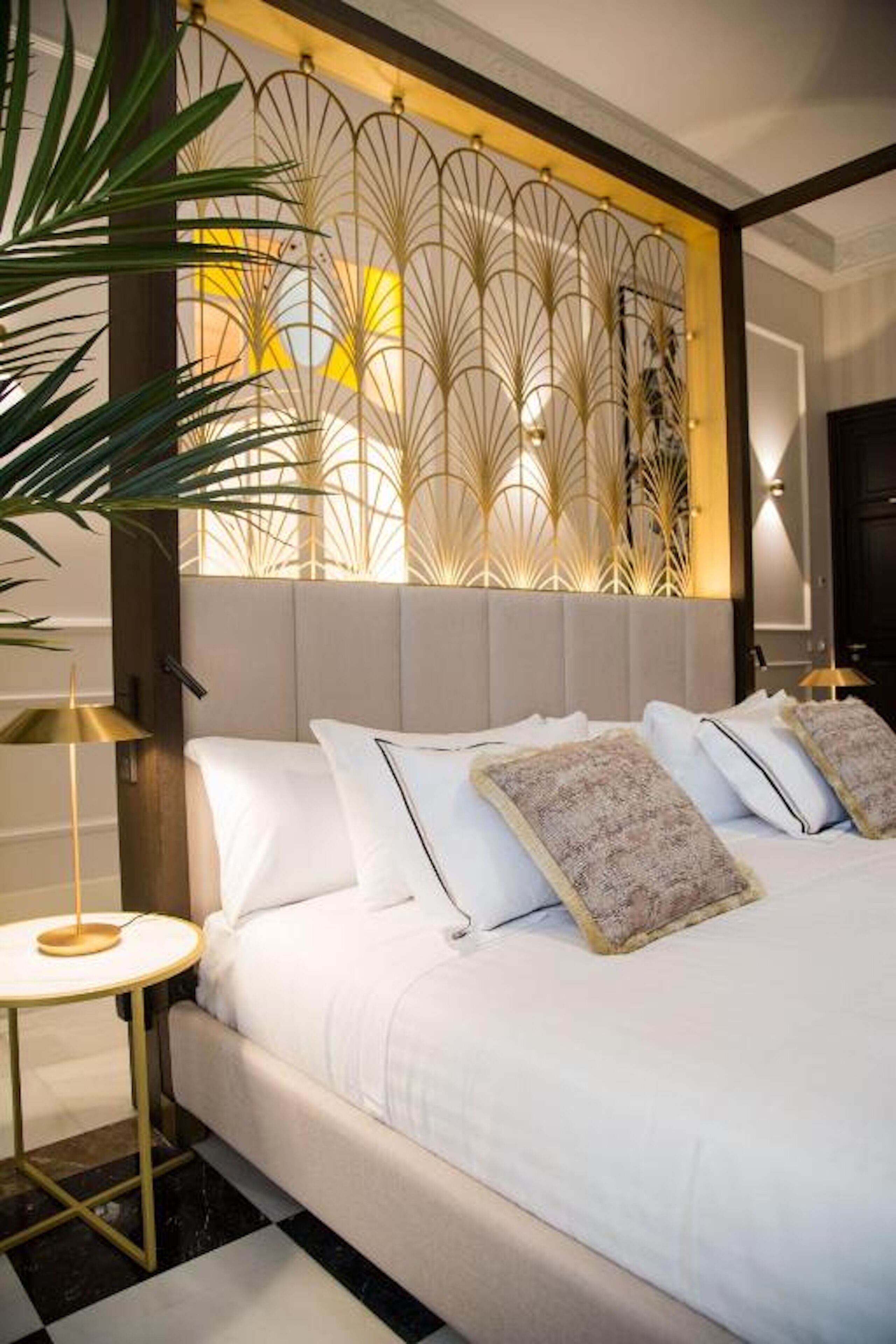 Un dormitorio moderno con una cama grande, un cabecero decorativo y una mesita de noche pequeña.