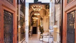 The entrance of the Palacio Vallier hotel with a grand archway, chandeliers, and a seating area inside. - MYR Palacio Vallier (Valencia)