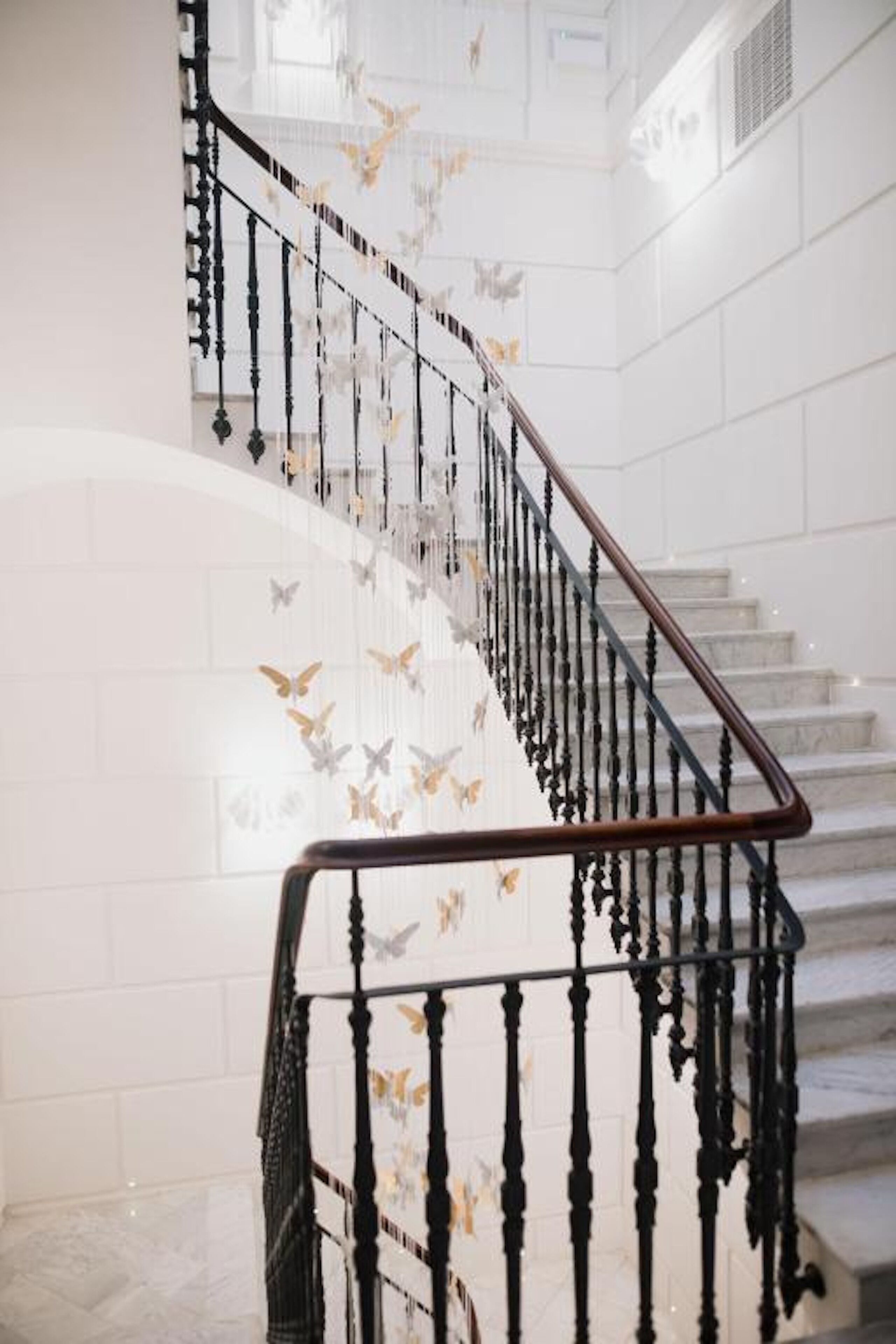 A staircase with black balusters and a white wall with butterfly decals.