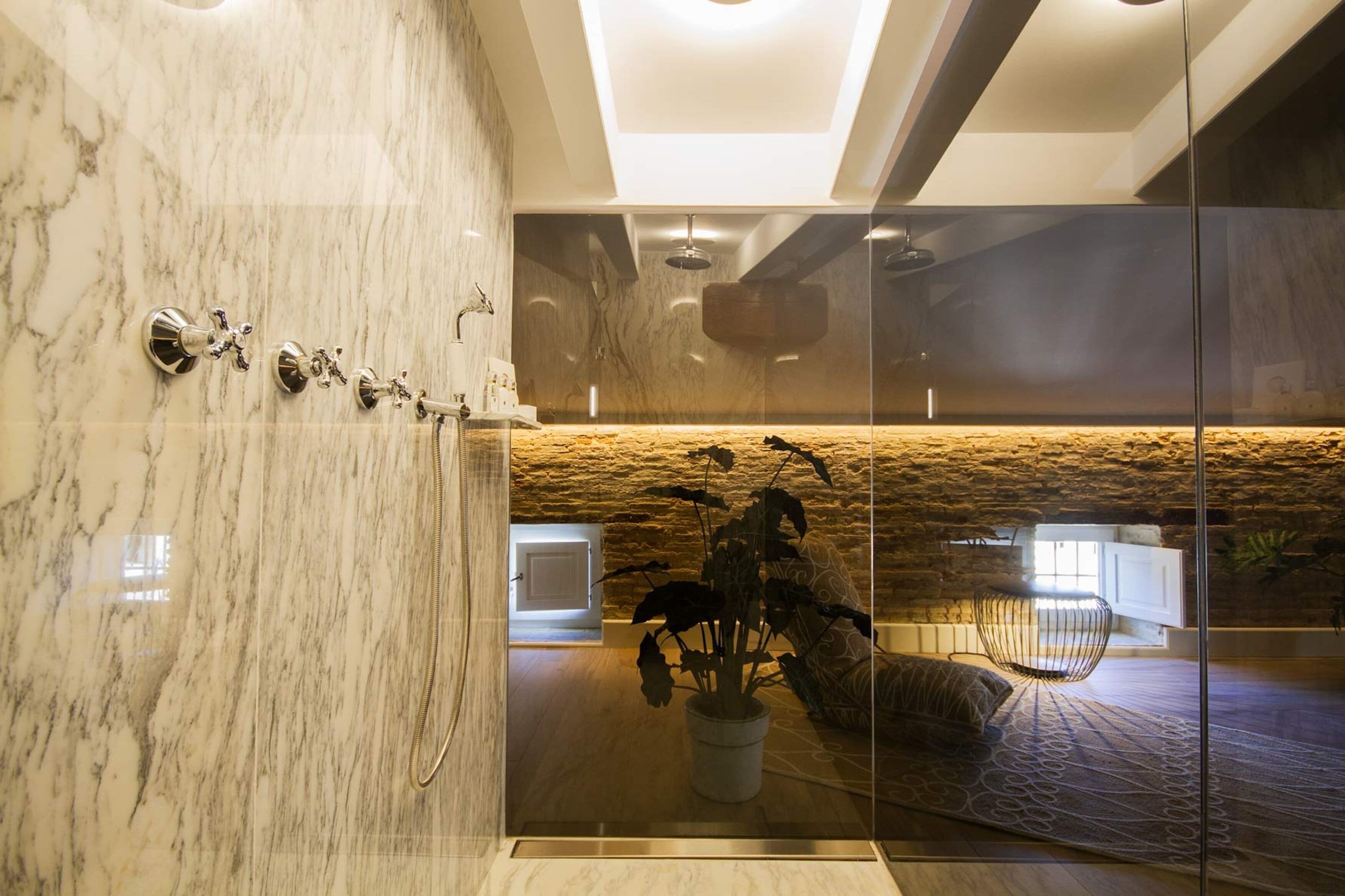 Un baño moderno con cabina de ducha de vidrio, paredes de mármol y una pared de acento de piedra.