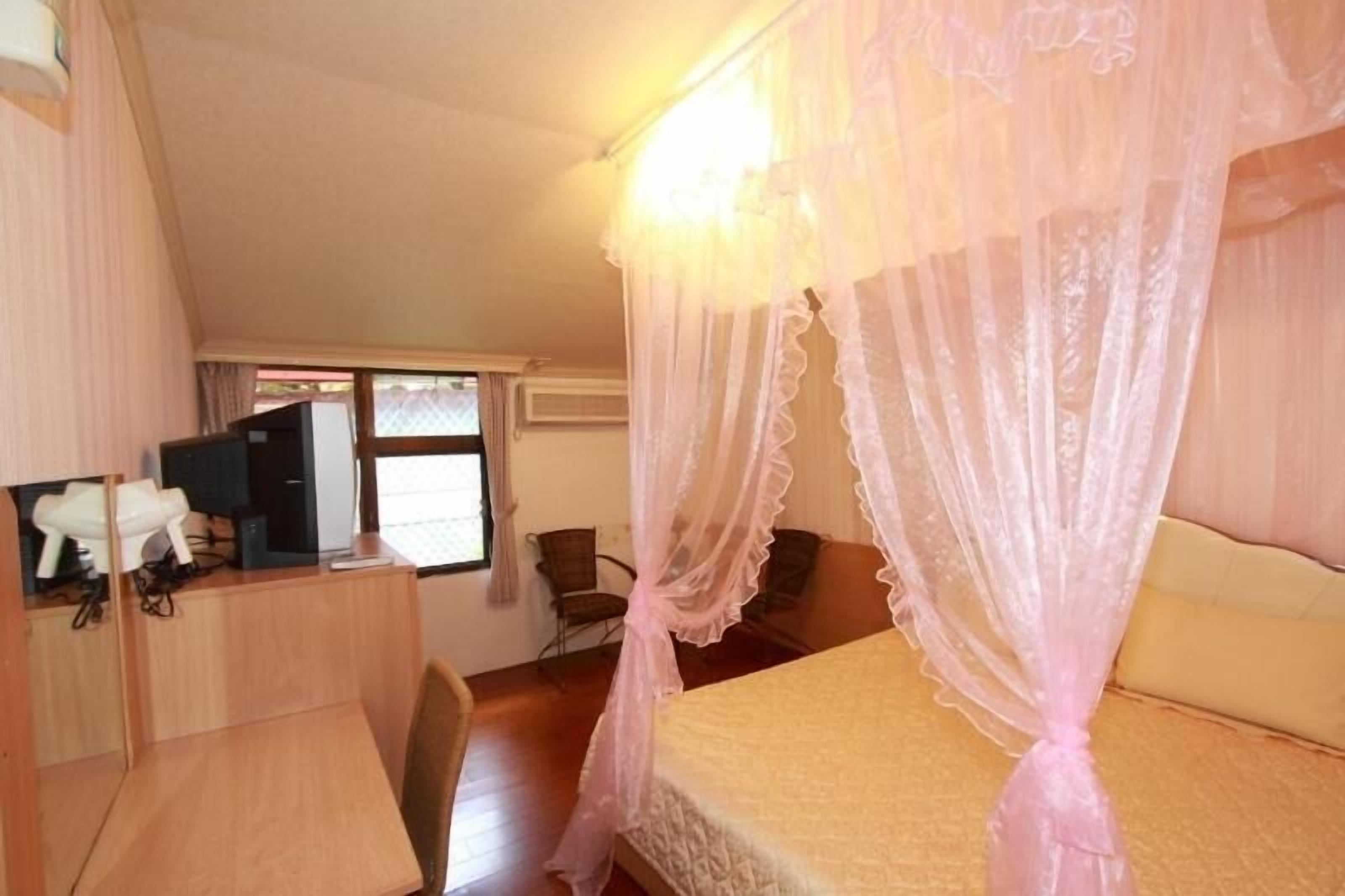 Une chambre à coucher avec un lit à baldaquin, un bureau, une chaise et un téléviseur.