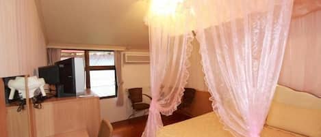 Une chambre à coucher avec un lit à baldaquin, un bureau, une chaise et un téléviseur.