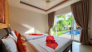 A hotel room with two beds, a ceiling fan, and a view of a swimming pool.
