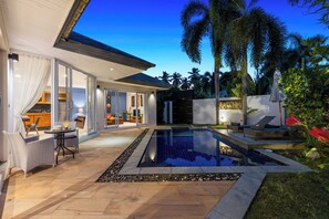 A modern house with a swimming pool, outdoor seating, and a patio area.