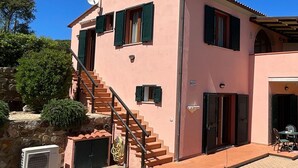A two-story pink villa with a staircase, a covered porch, and a satellite dish. - Appartamenti La Risacca - Appartamenti La Risacca - Trilo 4 VM (Capoliveri)
