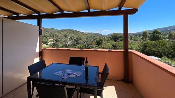 A covered outdoor area with a table and chairs, overlooking a scenic landscape. - Appartamenti La Risacca - Appartamenti La Risacca - Trilo 4 VM (Capoliveri)