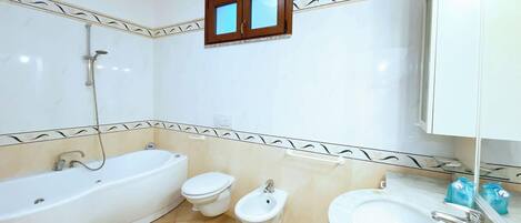 A bathroom with a bathtub, toilet, bidet, and sink.