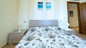 Una camera da letto con parete a righe, un letto con copripiumino floreale, un comodino con lampada e due quadri appesi sopra il letto.
