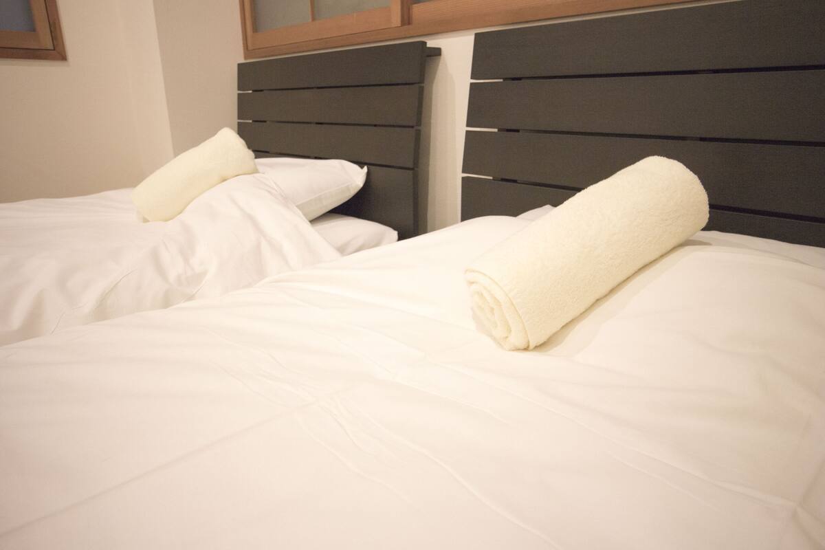 Two beds with white linens and a dark headboard.
