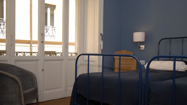 Una habitación con dos camas, un aparador de madera y una silla.