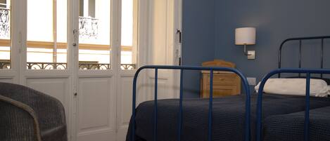 A room with two beds, a wooden dresser, and a chair.