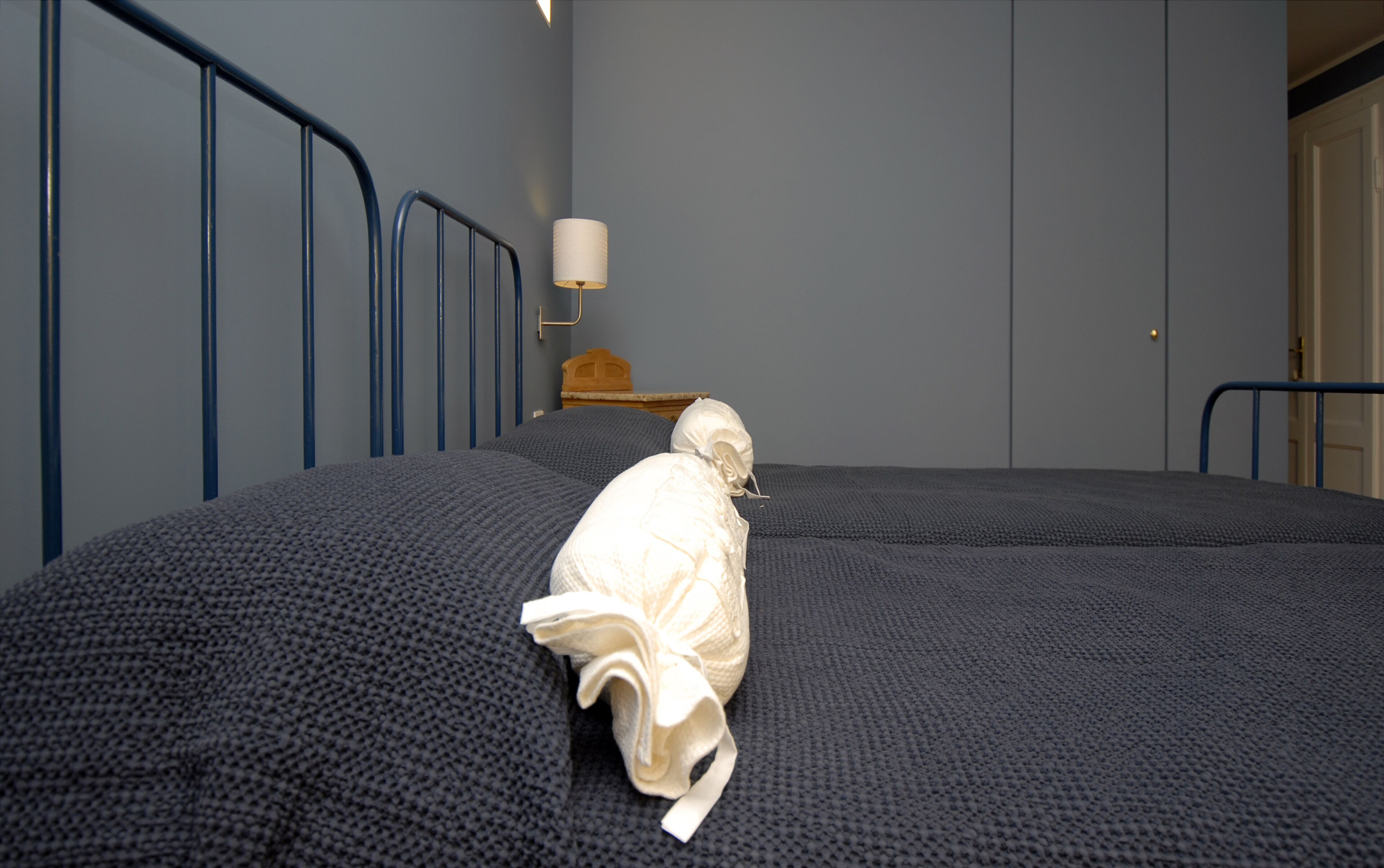 A room with a bed, a wall-mounted lamp, and a door.