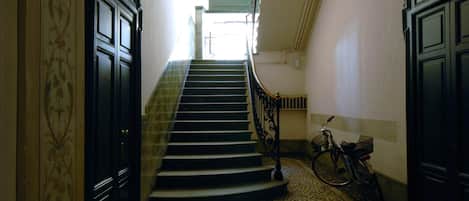 A staircase with a handrail, a bicycle, and a patterned floor.