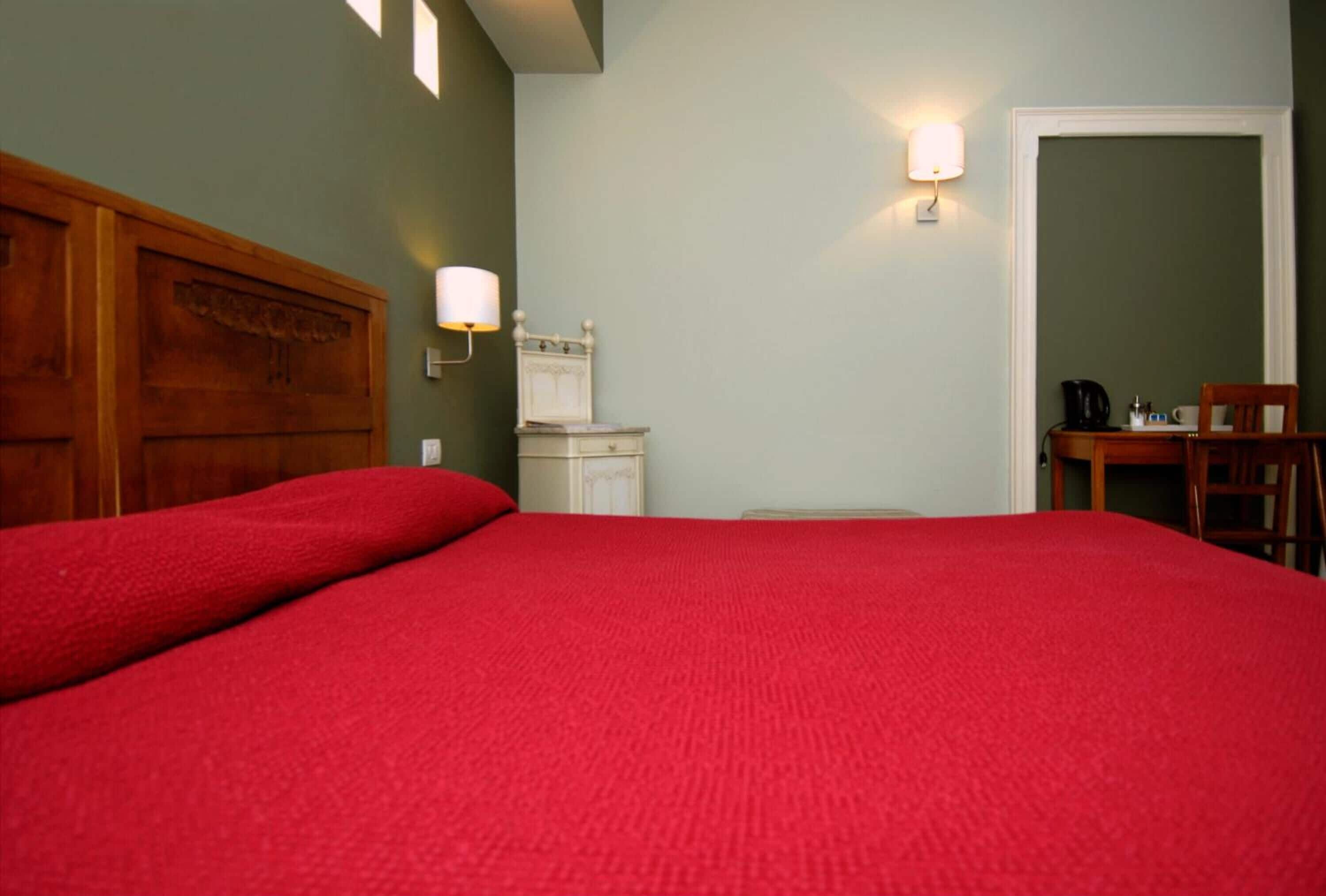 Una stanza con un letto grande, una testiera in legno, un comodino con una lampada e una sedia.
