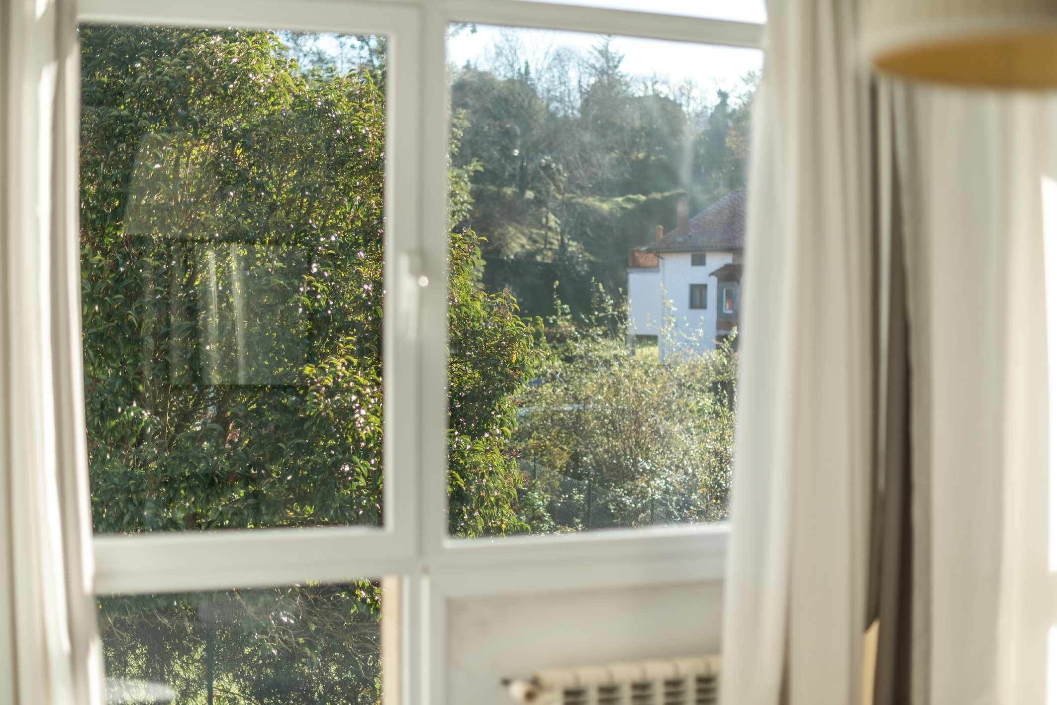 A window with a view of a house and trees.