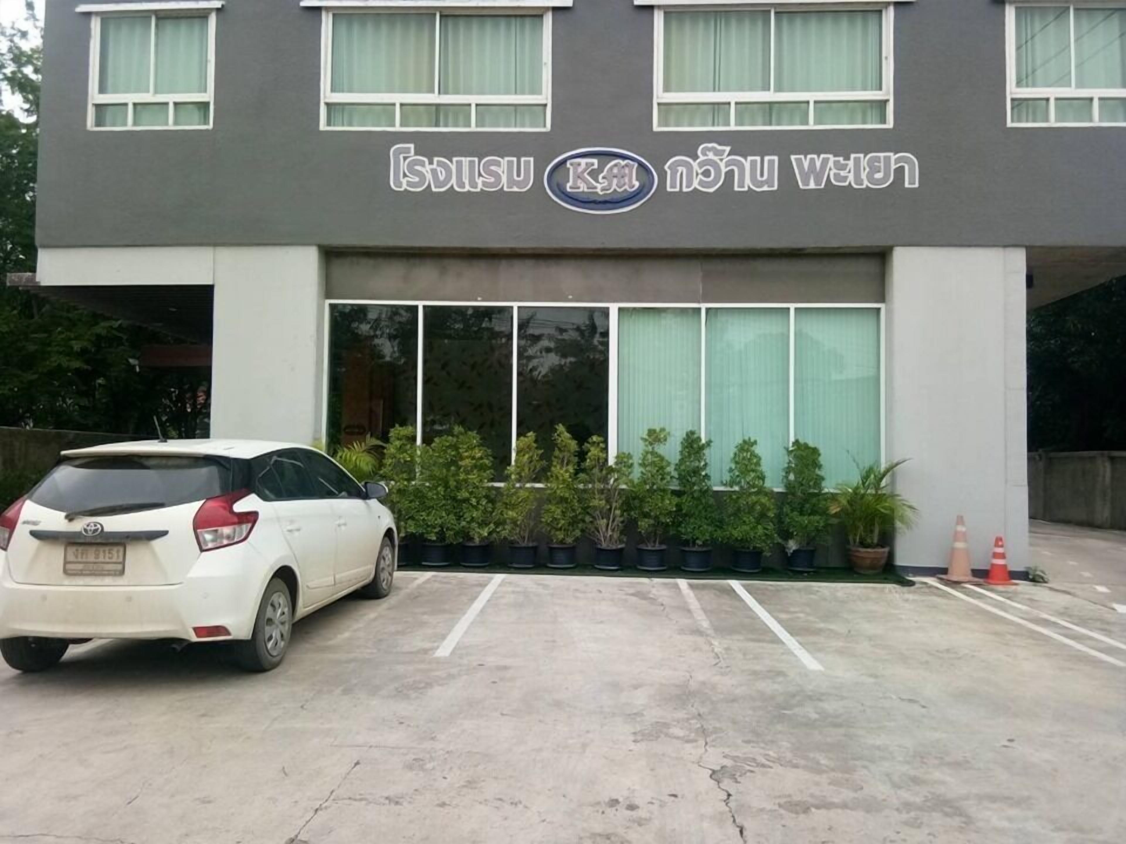 Un edificio con un letrero que dice "Isisu Khao" y un coche blanco estacionado al frente.