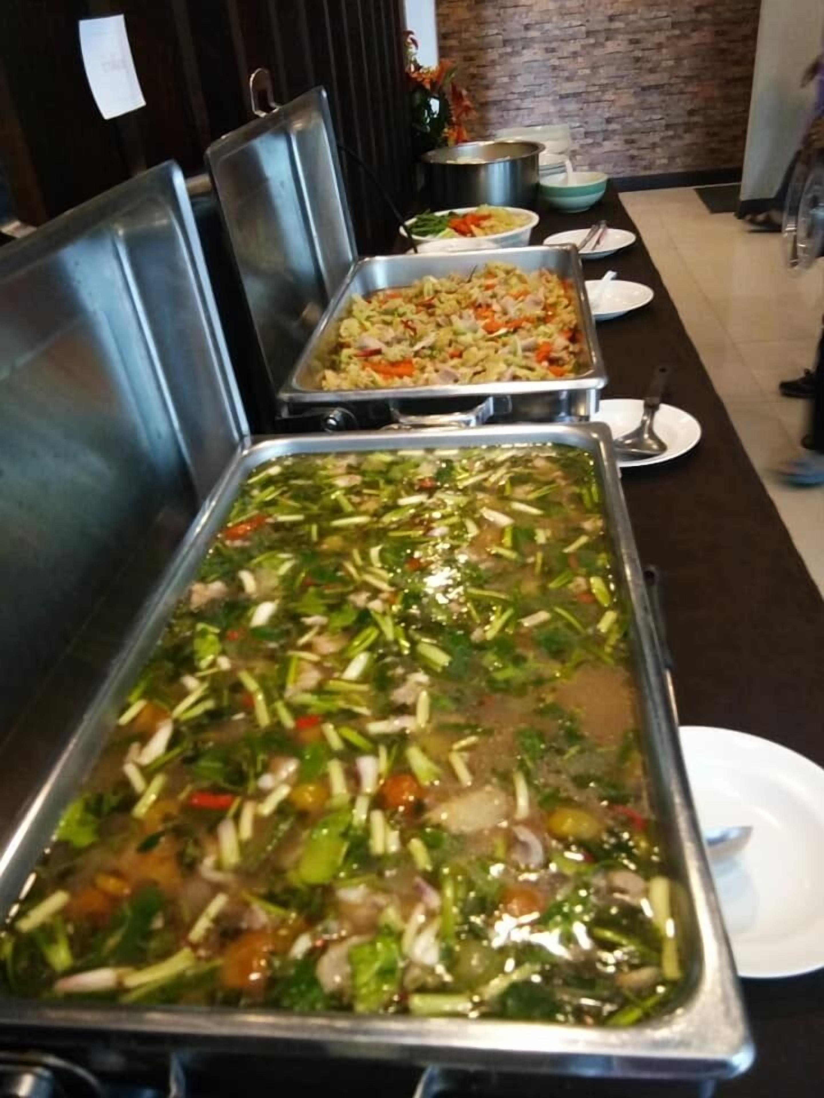 A buffet with various dishes, including a large pot of soup and a tray of fried rice.