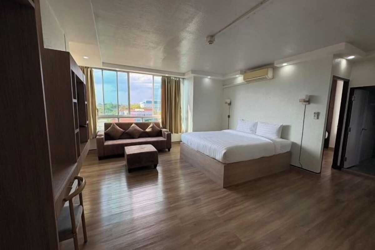Una habitación de hotel con una cama grande, un sofá, un escritorio y vistas a la ciudad.