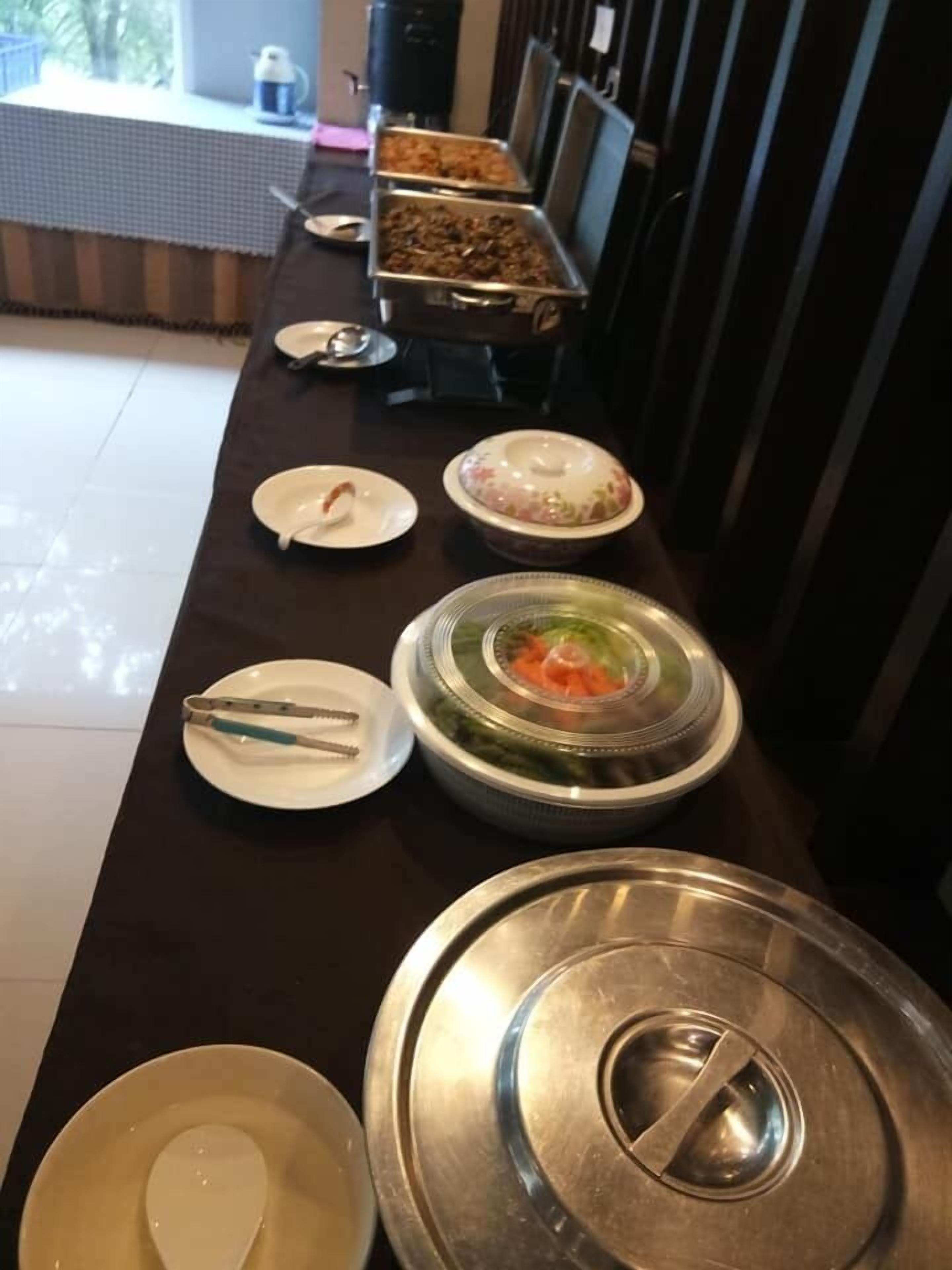 A buffet setup with various dishes and utensils on a long table.