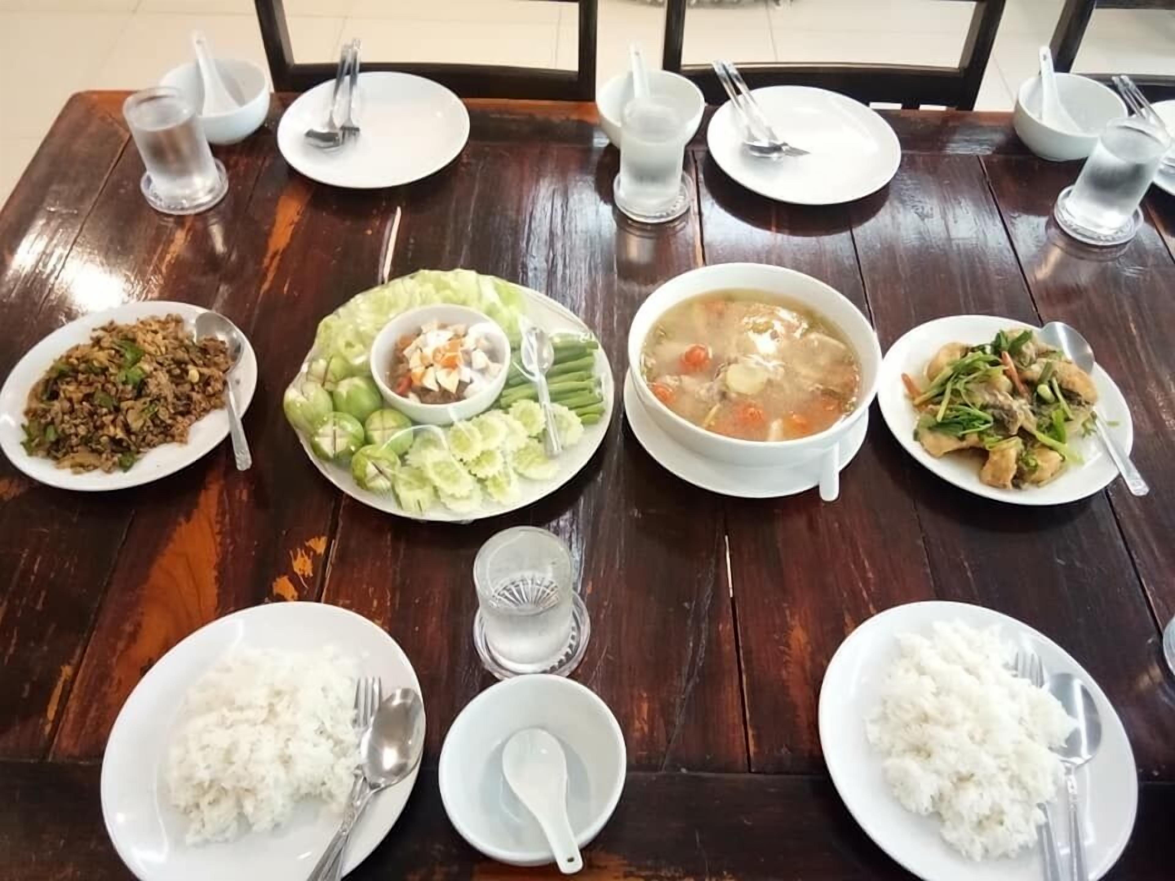 Una mesa de madera con cuatro platos de comida, dos cuencos y dos vasos de agua.