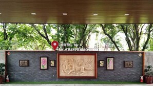 A building entrance with a stone wall, a large relief sculpture, and framed pictures. - KM Kwanphayao Hotel (Phayao)