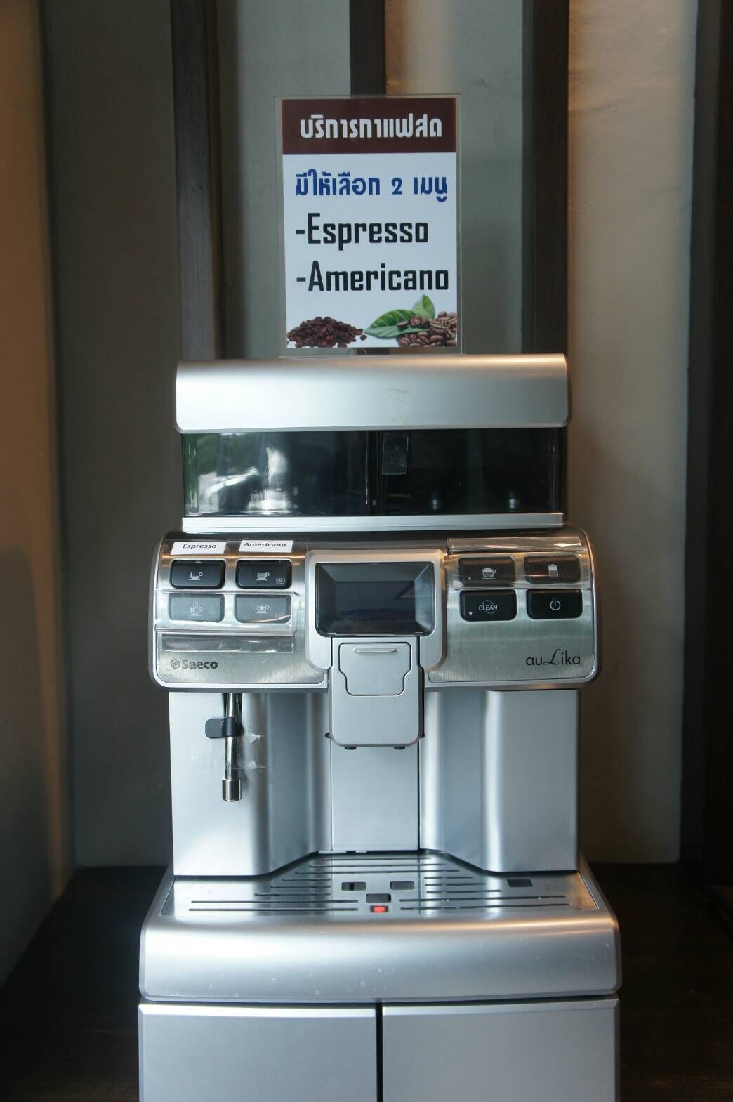 Una máquina de café con opciones de espresso y americano, y un cartel que indica el precio.