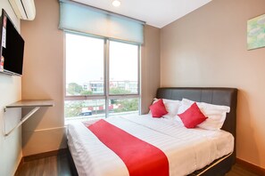 A hotel room with a large bed, a TV mounted on the wall, and a window with a view of buildings outside. - OYO 90282 Hotel Taj (Shah Alam)
