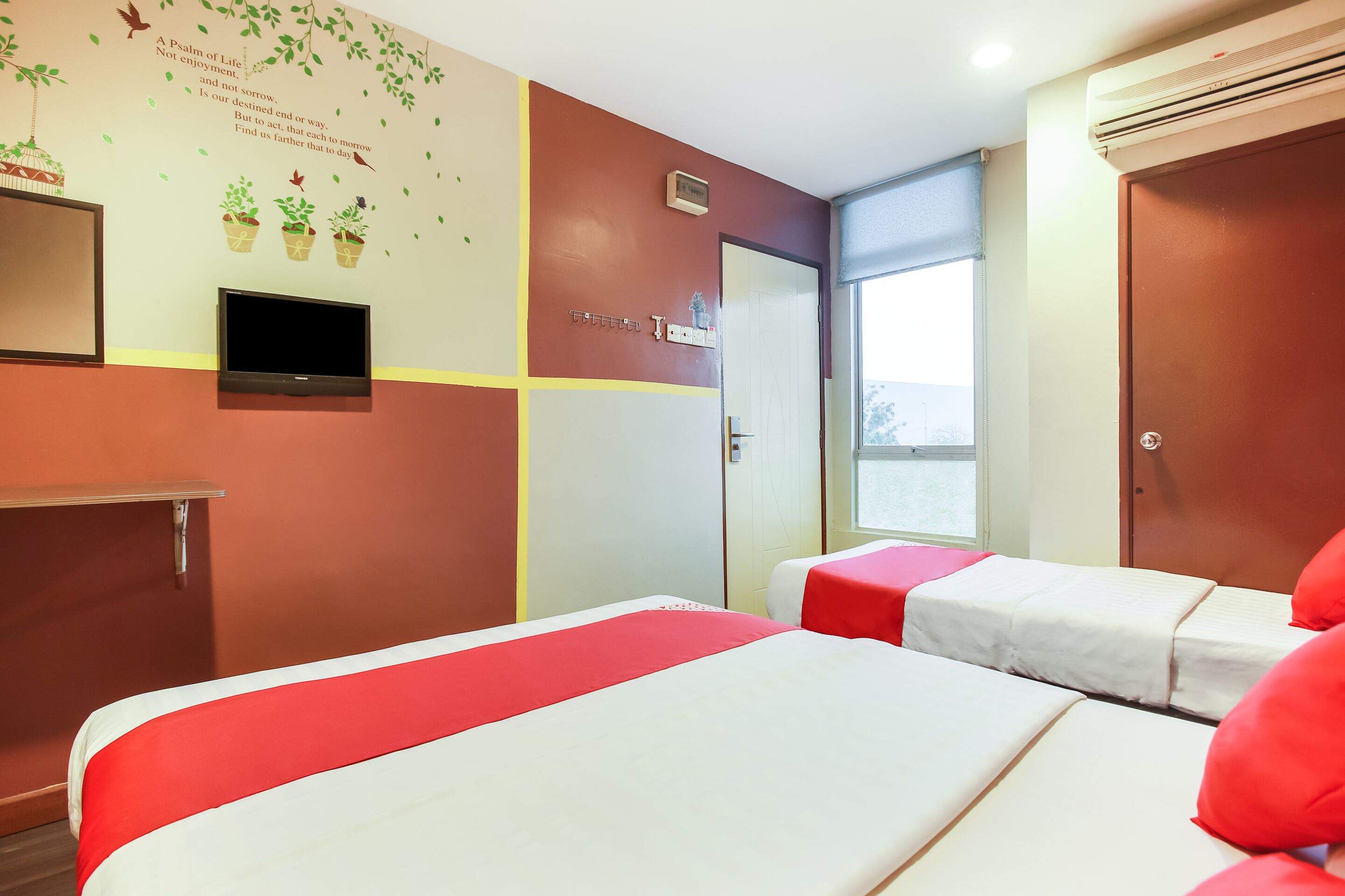 A hotel room with two beds, a television, a window, and a wall with a decorative design.